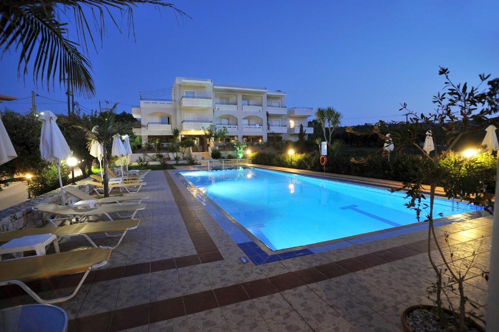 a swimming pool in front of a hotel at night at Merabello Apartments in Agia Marina Nea Kydonias