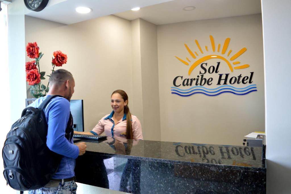 un hombre y una mujer de pie en un hotel de autoservicio en Sol Caribe Hotel, en Soledad