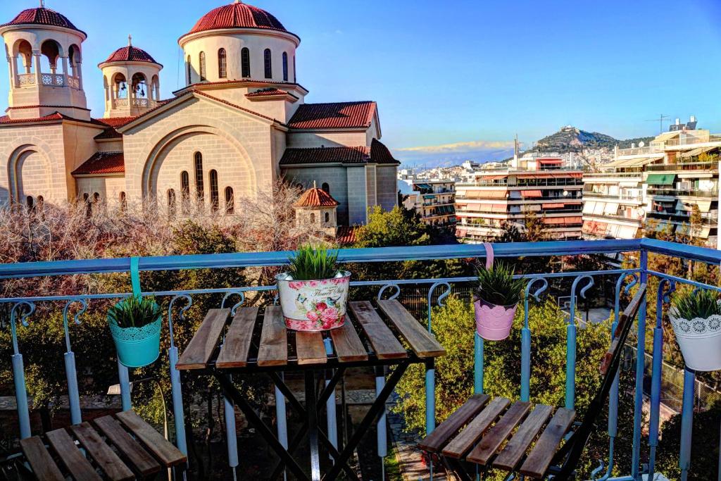 a balcony with a table and potted plants and a church at Fairytale view of Lycabettus in Athens