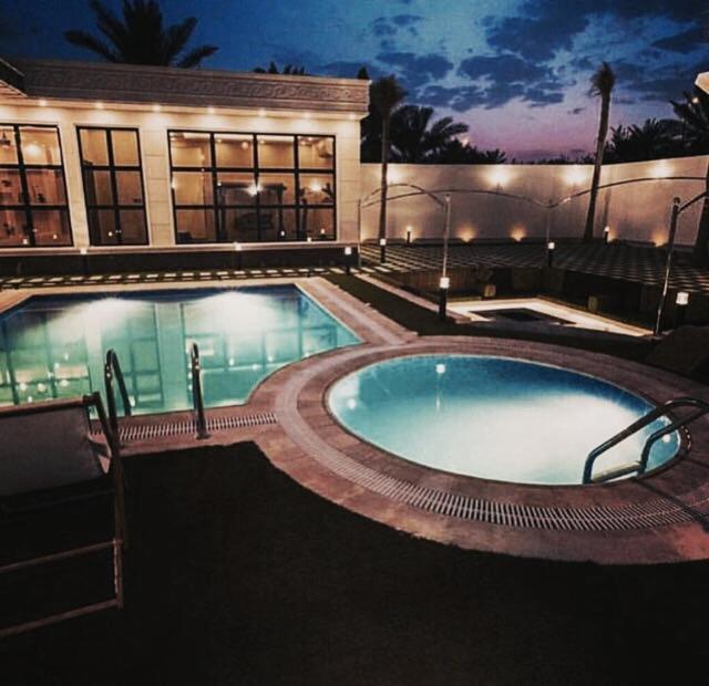 a swimming pool in front of a building at night at شالية النخلة in Unayzah