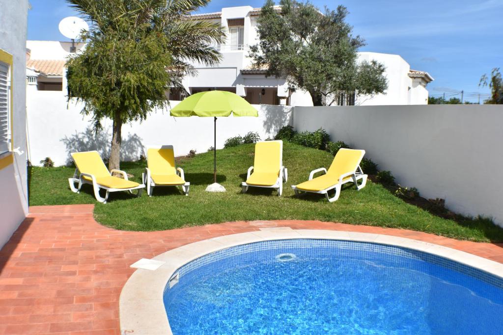 a group of chairs and an umbrella and a swimming pool at Villa Amendoeira-POOL HEATED in Guia
