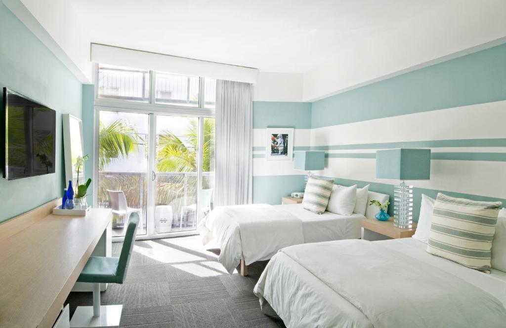 
a hotel room with two beds and two windows at The Local House in Miami Beach
