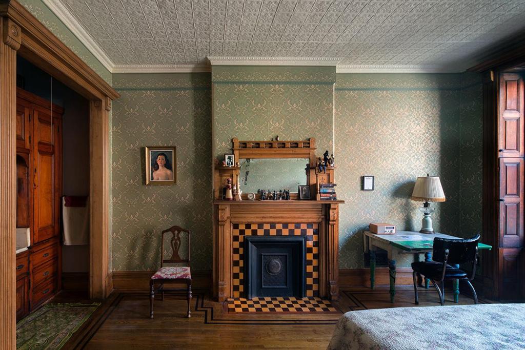 紐約的住宿－哈林福羅普小屋酒店，一间卧室设有壁炉、桌子和床。