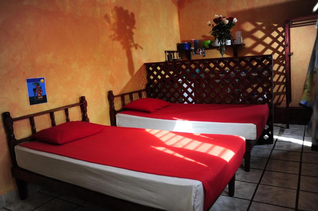 two beds in a room with red sheets at Hotel Colorado in Playa del Carmen