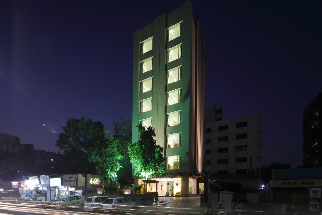 a tall green building with lights on it at night at Hotel 440, A Serene Stay in Ahmedabad