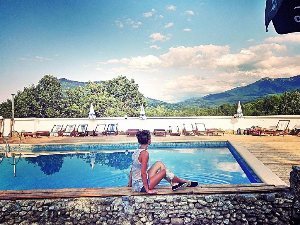 una persona sentada junto a una piscina en Hotel Tihiat Kat en Apriltsi