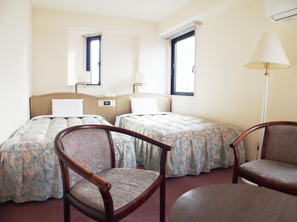 a hotel room with two beds and two chairs at Hotel Park Avenue in Tokyo