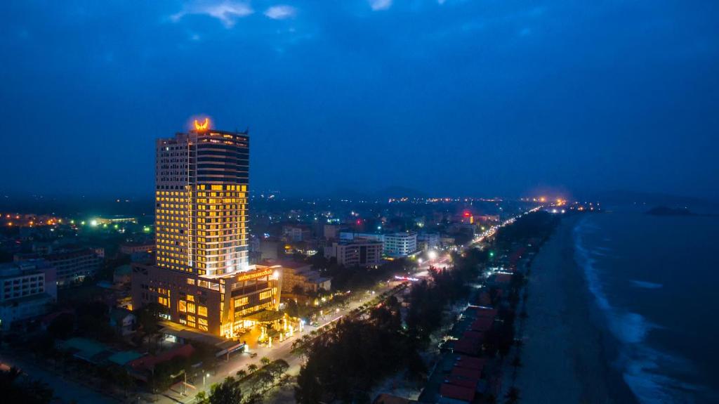 um edifício alto com luzes em cima à noite em Muong Thanh Grand Cua Lo Hotel em Cửa Lô