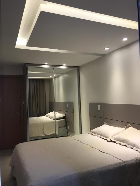 1 dormitorio con 2 camas y un espejo grande en Apartamento, en Arraial do Cabo
