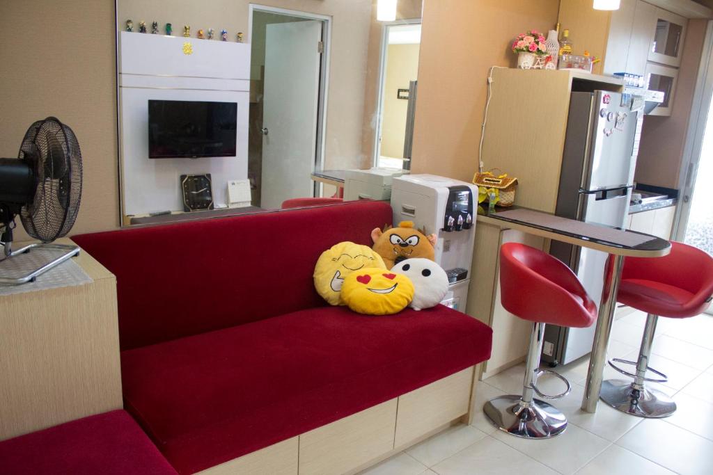 two stuffed animals are sitting on a red couch at Green Bay Pluit Apartment - Indra in Jakarta