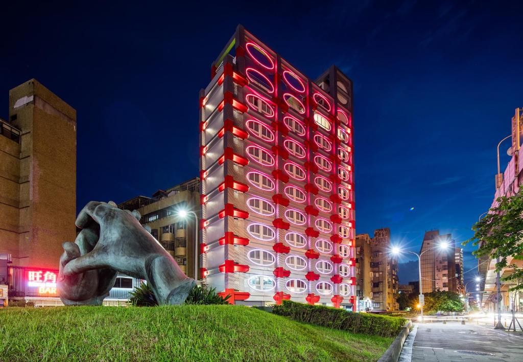 台北的住宿－Hotelpoispois泡泡飯店，一座高大的红色建筑,前面有雕像