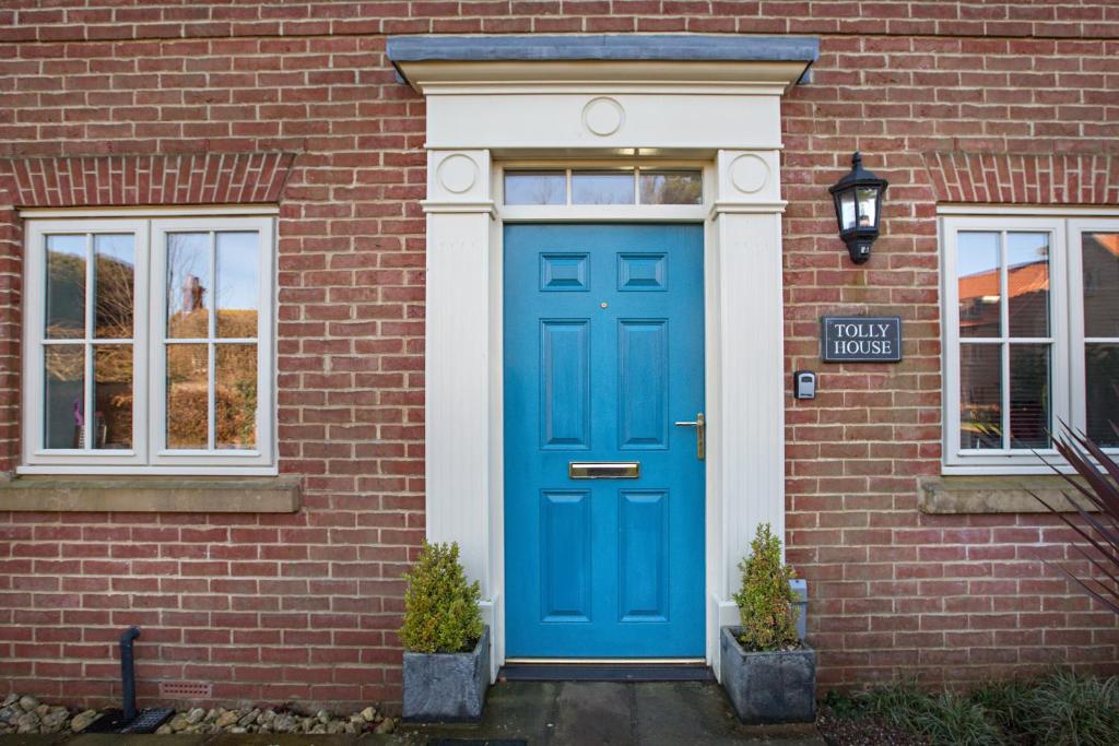 a blue door on a brick building with a street sign at Tolly House in Wells next the Sea