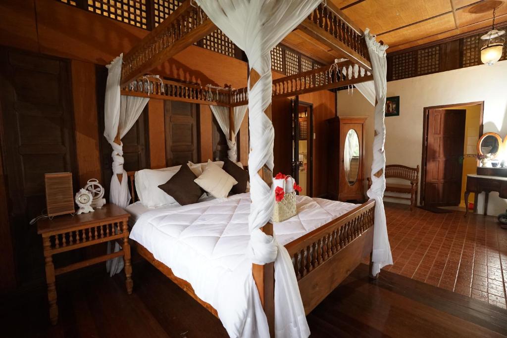 a bedroom with a canopy bed with white sheets at Plantacion Isabelle in Taal