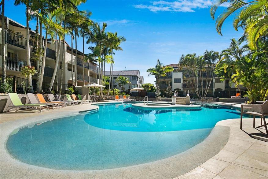a large swimming pool with chairs and palm trees at Noosa Beach Apartment on HASTING ST French quarter resort.Noosa Heads in Noosa Heads
