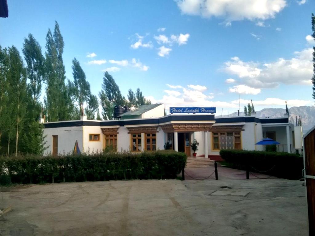 a large white building with trees in the background at Hotel Ladakh Heaven in Leh