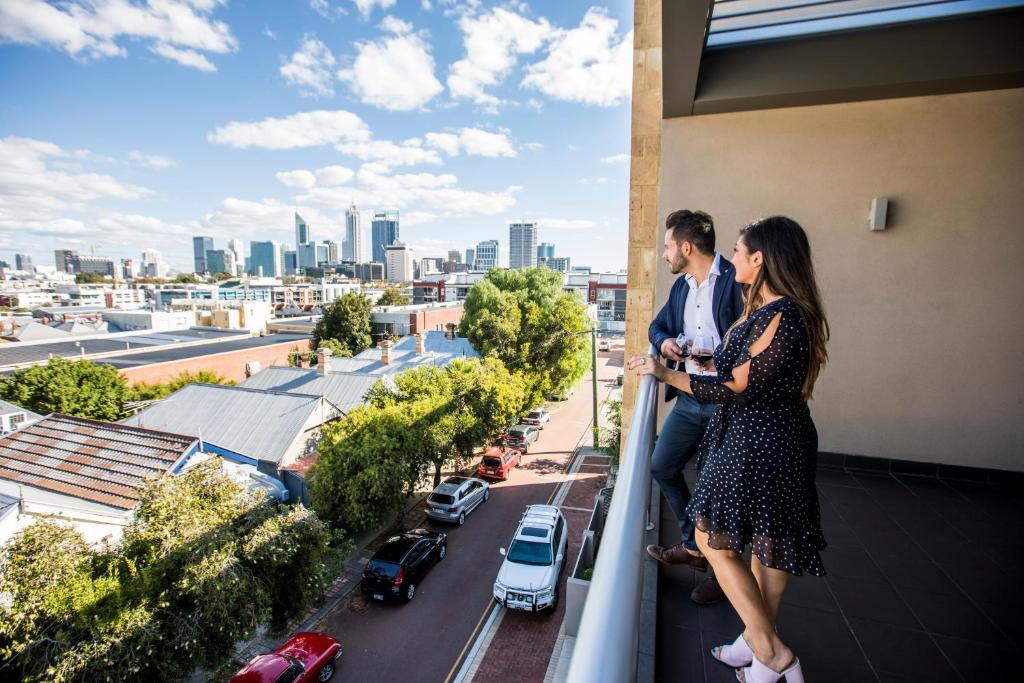 mężczyzna i kobieta stojący na balkonie z widokiem na miasto w obiekcie Zappeion Apartments w mieście Perth