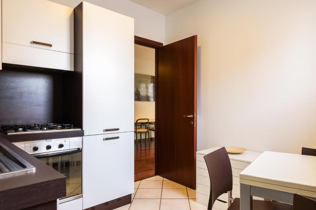 ミラノにあるMagistretti Flexyrent Apartmentの白いキャビネットとテーブル付きのキッチン
