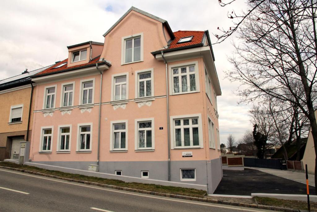 ein rosafarbenes Gebäude an der Straßenseite in der Unterkunft Triangle Apartments in Gießhübl