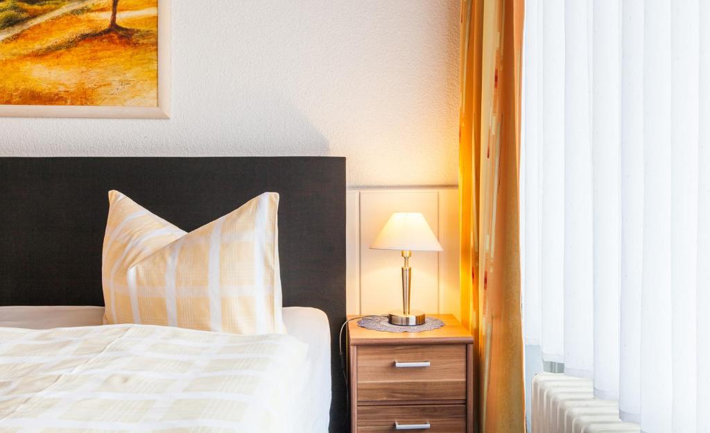 a bedroom with a bed and a lamp on a night stand at Hotel Quellental in Pinneberg