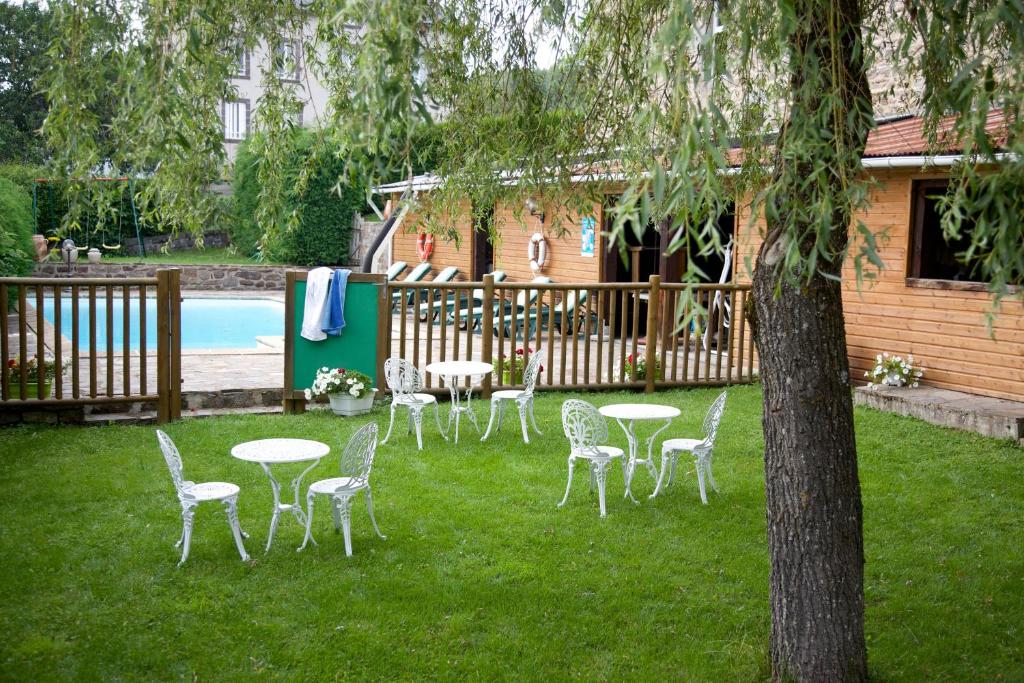 um grupo de mesas e cadeiras num quintal com piscina em logis hôtel Le petit breuil em La Courtine