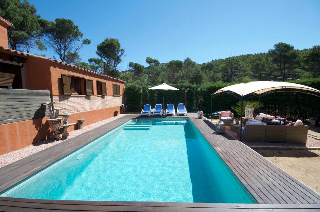 a swimming pool with chairs and umbrellas next to a building at Villa Bel in Begur