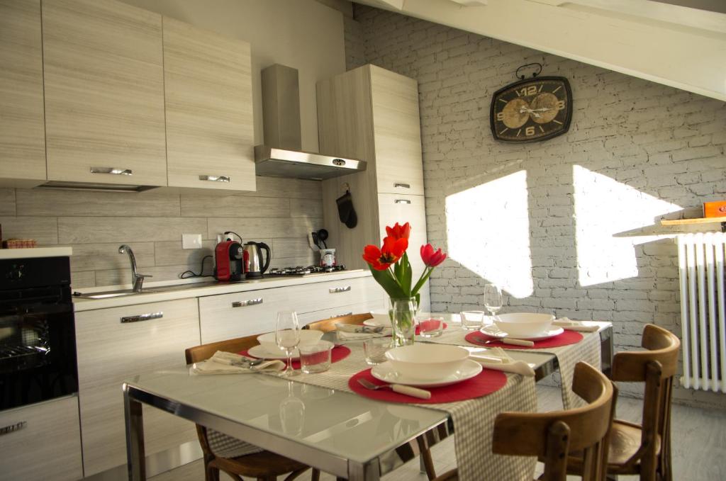 een keuken met een tafel met rode bloemen en een klok bij Il nido del Picchio in Turijn