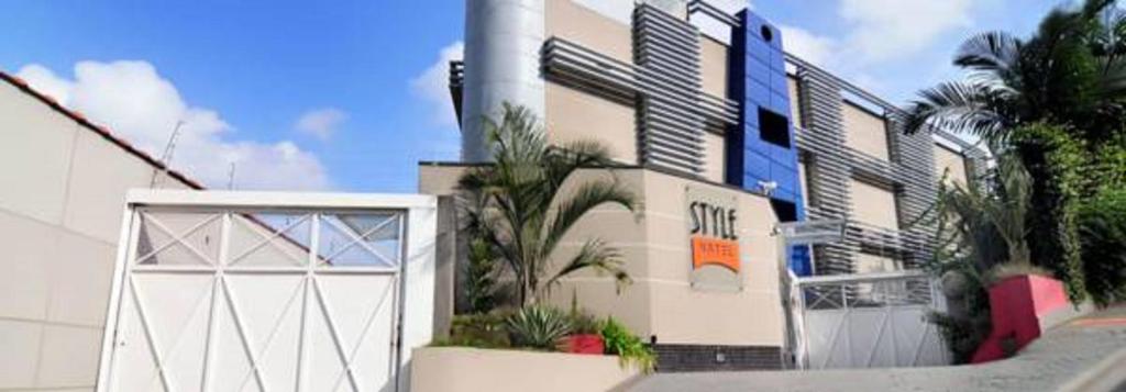 a white building with a white gate and palm trees at Style Hotel ( Adults Only) in Sao Paulo