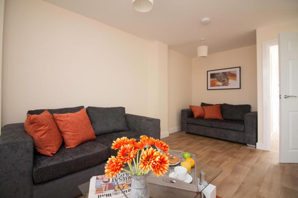 - un salon avec un canapé et une table avec des oreillers orange dans l'établissement DPV - Above Bar Street Apartments, à Southampton