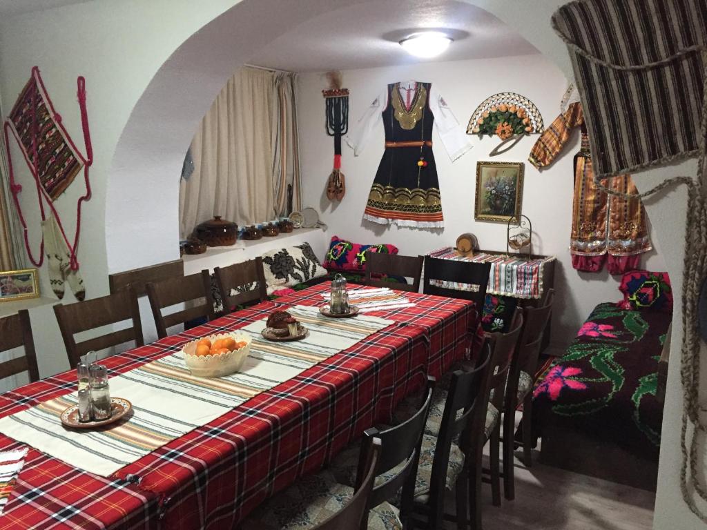 uma sala de jantar com uma mesa e cadeiras com um vestido na parede em Elenite Guesthouse em Gotse Delchev