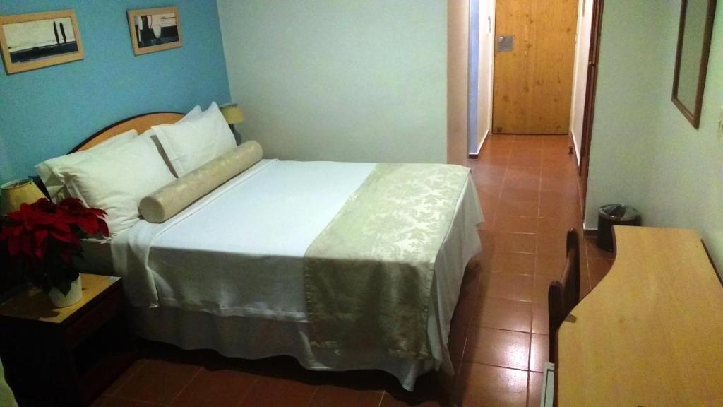
a bedroom with a bed and a table at Hotel Torremolinos in Ubatuba
