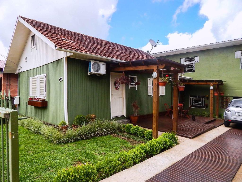 Casa verde y blanca con terraza de madera en Residenciais Vista do Centro Gramado, en Gramado