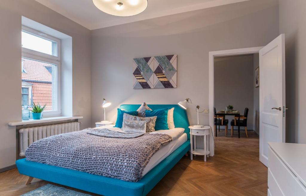 a bedroom with a blue bed and a table at Greystone Suites & Apartments in Riga