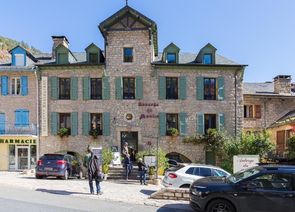 a large stone building with cars parked in front of it at Auberge du Moulin in Sainte-Énimie