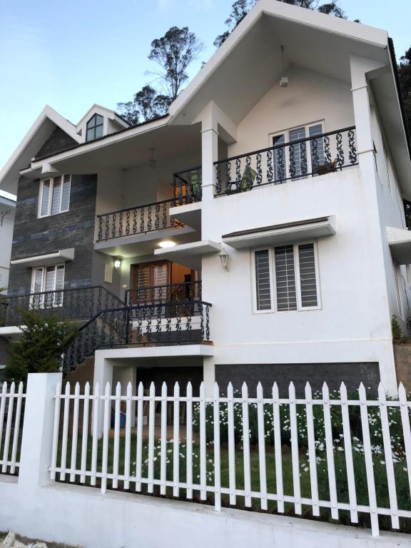 a house with a white fence in front of it at Aanvis inn in Ooty