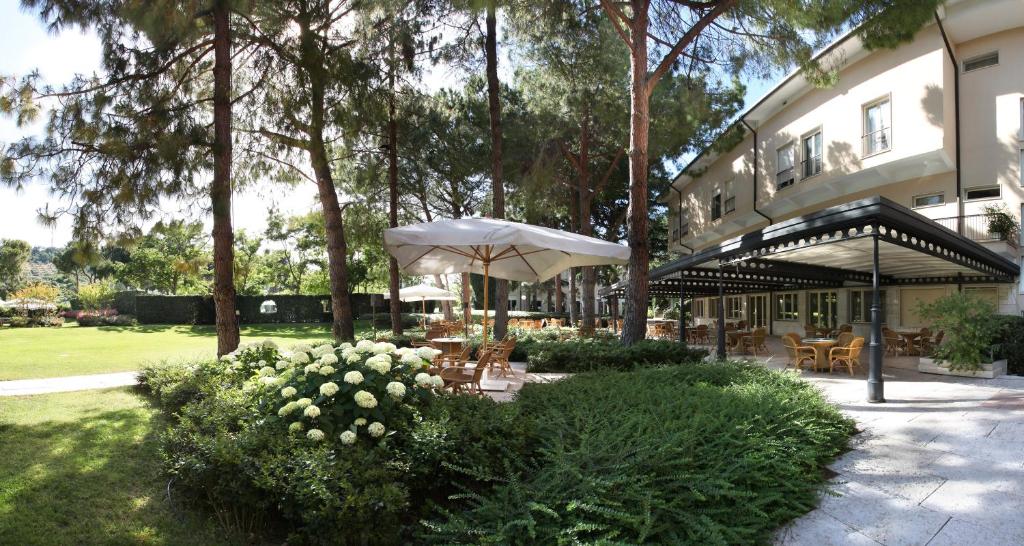 a patio with an umbrella and tables and chairs at Villa Maria Hotel & SPA in Francavilla al Mare