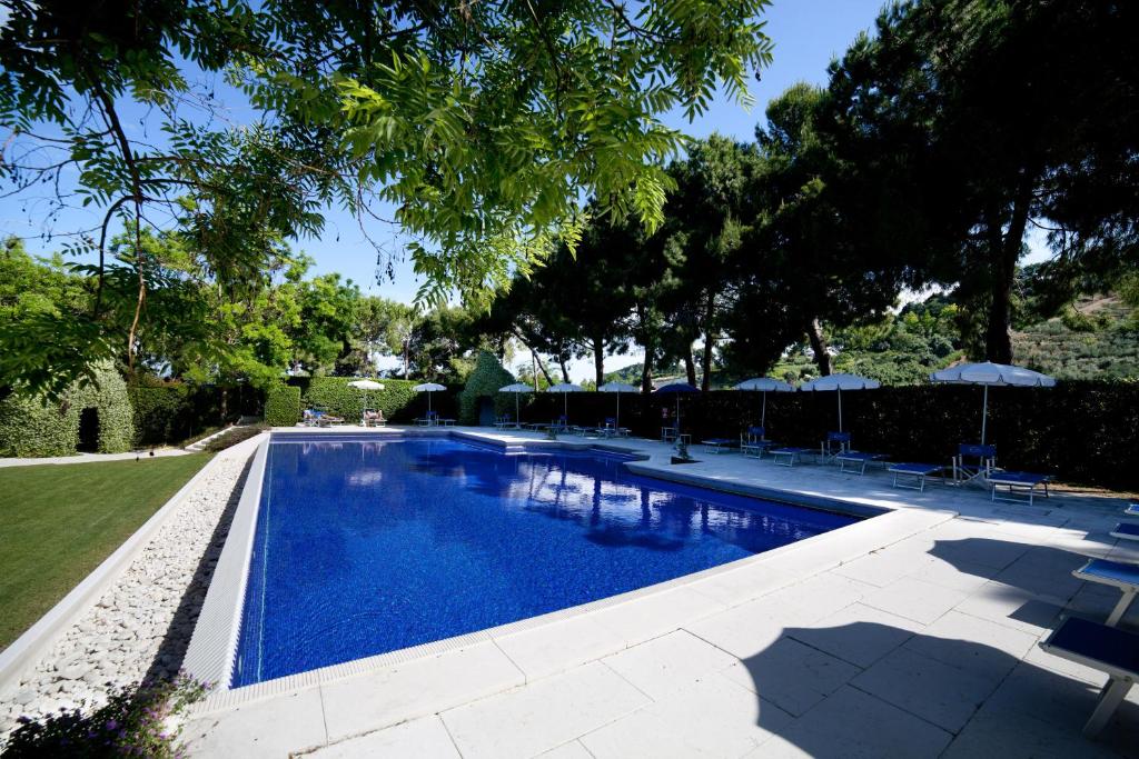 a swimming pool with chairs and umbrellas in a yard at Villa Maria Hotel & SPA in Francavilla al Mare