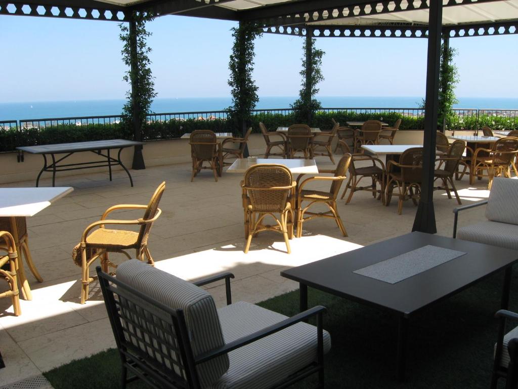 a patio with tables and chairs with the ocean in the background at Villa Maria Hotel & SPA in Francavilla al Mare