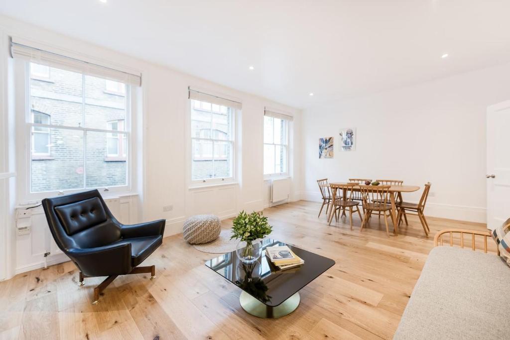 Covent Garden Apartments - Netflix and Nespresso في لندن: غرفة معيشة مع كرسي أسود وطاولة
