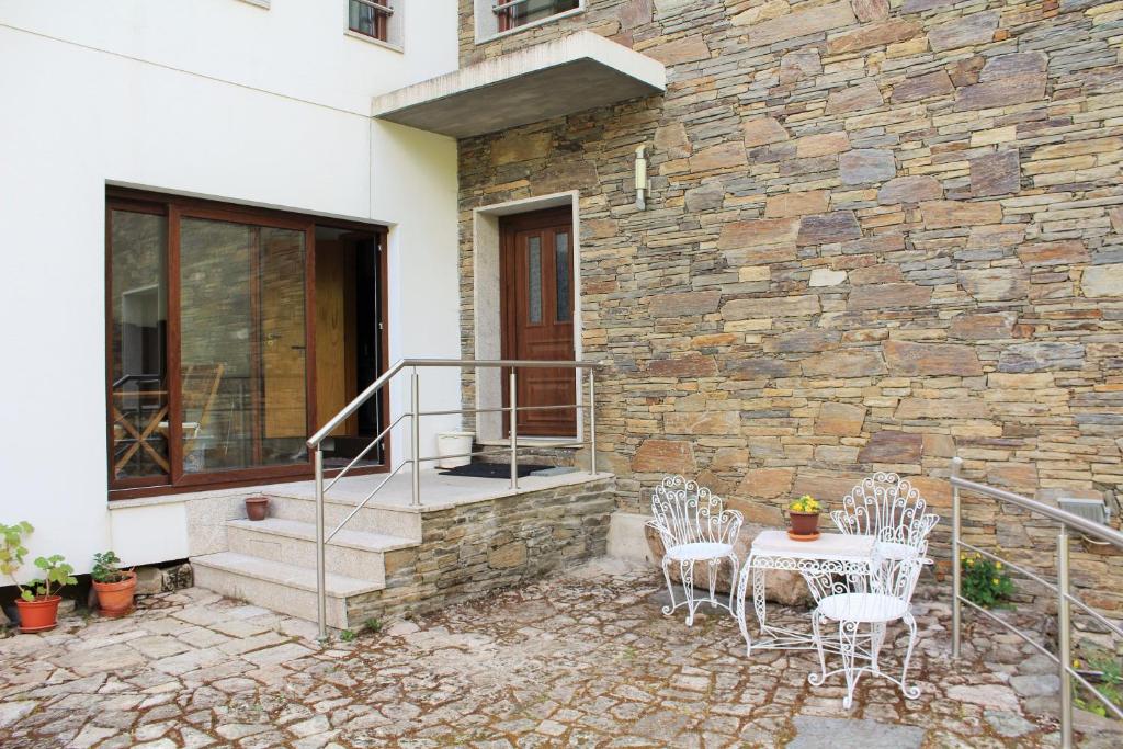 un patio con sedie e un tavolo e un muro di pietra di Moinho da Ponte Velha a Bragança