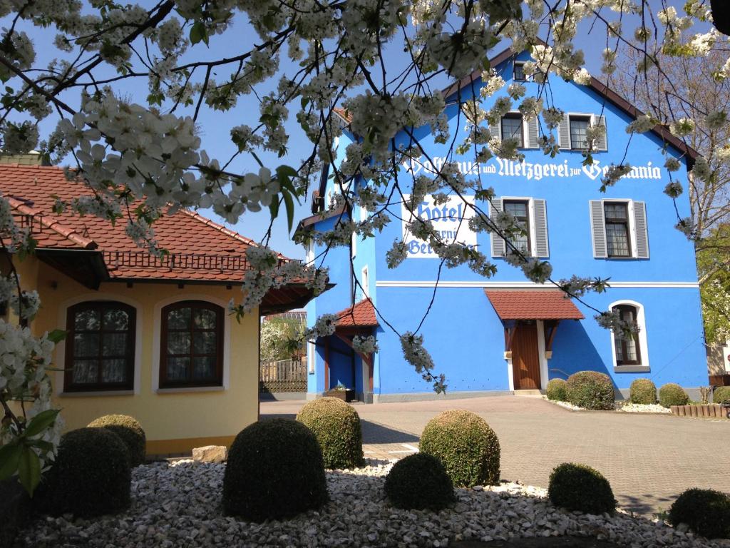 un bâtiment bleu avec des fleurs blanches devant lui dans l'établissement Hotel zur Germania, à Ostfildern