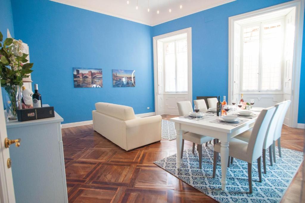 un comedor con paredes azules y una mesa y sillas blancas. en Italianflat - Palazzo Rizzardi, en Verona