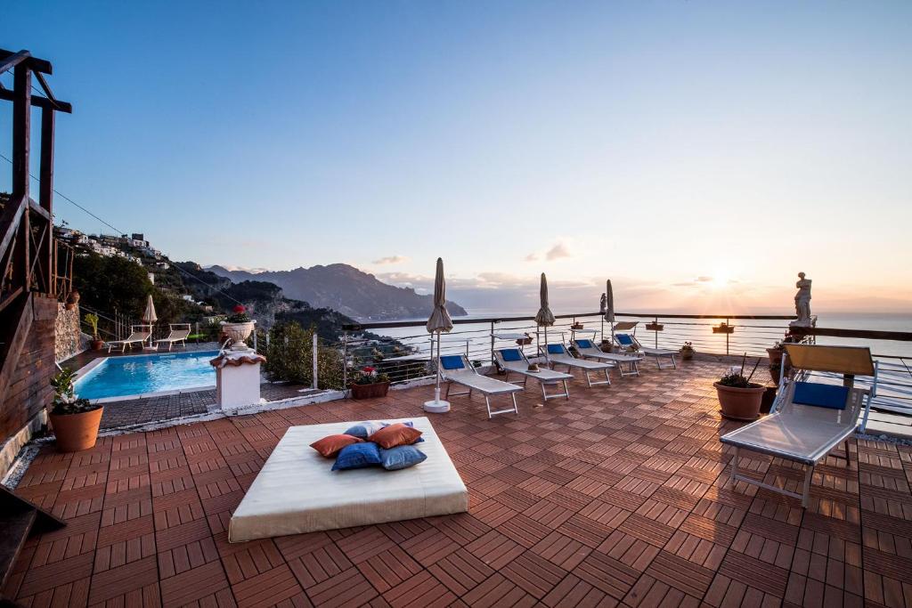 un patio all'ultimo piano con piscina e sedie a sdraio di Villa Gioiello ad Amalfi