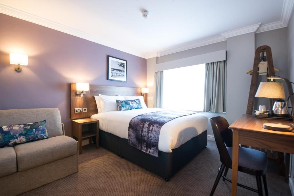 um quarto de hotel com uma cama, uma secretária e uma cadeira em The Swan by Innkeeper's Collection em Coleshill