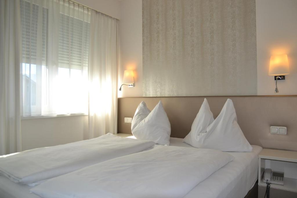 uma cama branca com almofadas brancas num quarto em Hotel Hecher em Wolfsberg