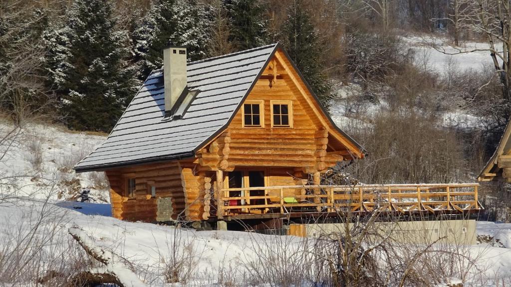 domek z bali na śniegu z dachem w obiekcie CzapaDziada w mieście Zatwarnica