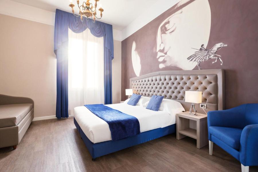 a bedroom with a bed and a blue chair at Hotel Ristorante Ala d'Oro in Lugo