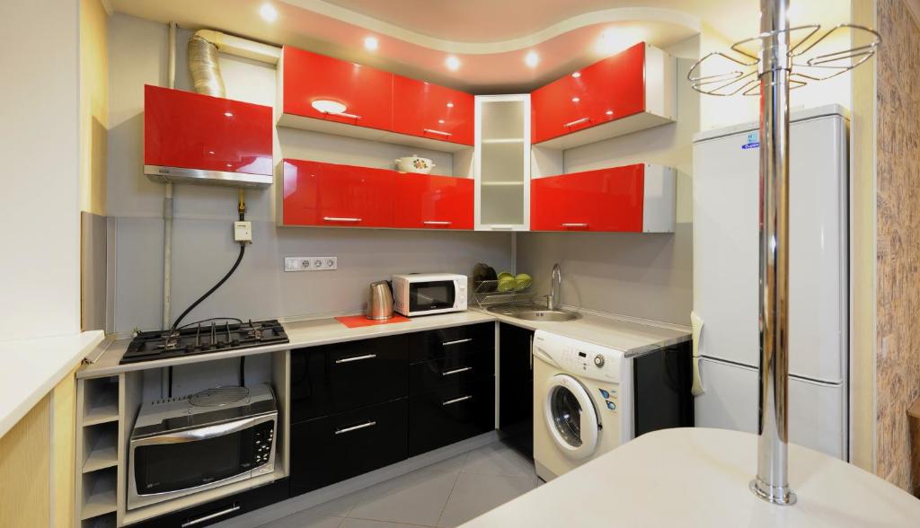オムスクにあるOmsk Sutki Apartments on Ilyicheva 6のキッチン(赤いキャビネット、洗濯機、乾燥機付)