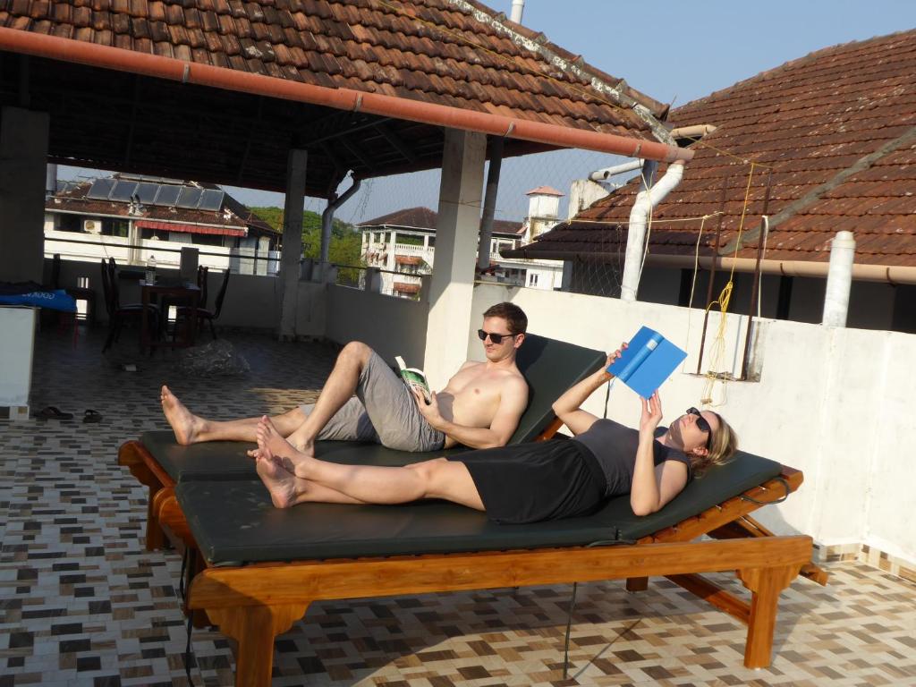 a man and a woman laying on a bed on a patio at La Lune Fort Kochi in Cochin