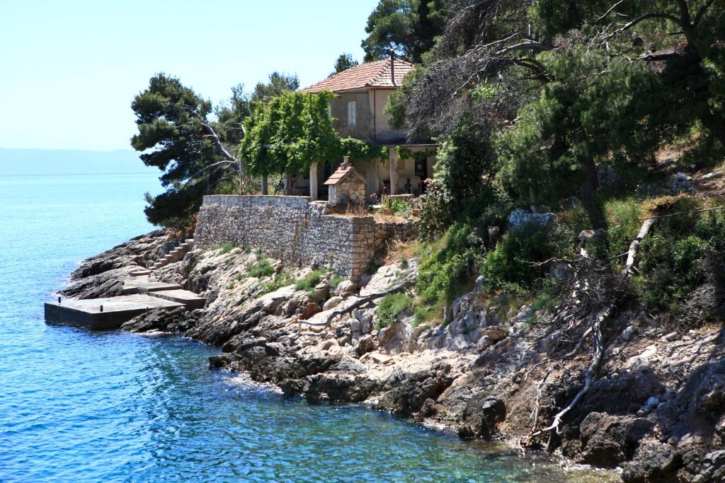 a house on a cliff next to the water at Robinson Artemis in Vela Luka