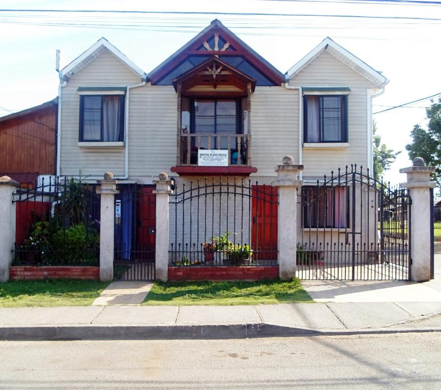 una casa blanca con una puerta roja en Hostal Plaza Maule Express, en Talca